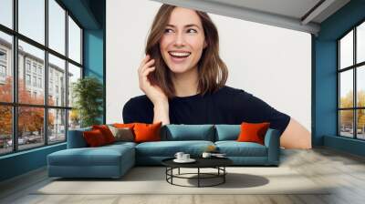 Portrait of young happy beautiful woman smiling and standing isolated on white background in a black t-shirt. Young female girl with a perfect smile looking left. Wall mural