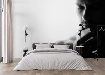 Handsome young man smelling bottle of perfume on white background Wall mural