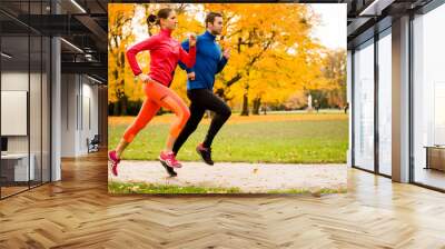 Couple jogging in autumn nature Wall mural