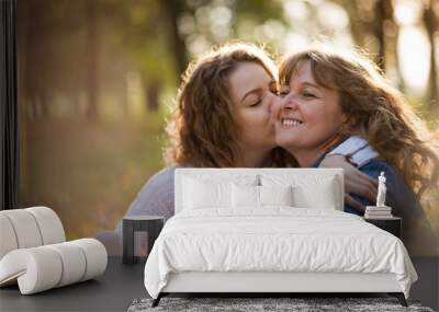 Senior woman is kissed by her adult daughter Wall mural