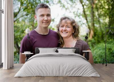 Smiling mother posing with adult son, outdoors. Wall mural