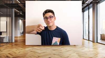 Young man with glasses pointing with index finger Wall mural