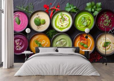 Assortment of colored vegetable cream soups. Vegetable soup set. Dietary food. On a black stone background. Top view. Wall mural