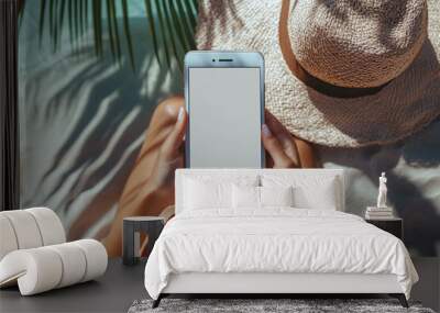 Mockup image of a woman holding and using mobile phone with isolated blank desktop screen white sitting on the beach Wall mural