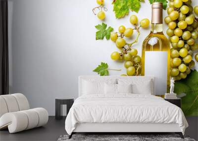 Unopened bottle of white wine with blank label, empty wineglass & bunches of different grapes on white background. Expensive bottle of chardonnay concept. Copy space, top view, flat lay Wall mural