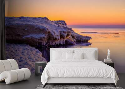 colorful beautiful sunset at sea in winter with snow on the beach Wall mural