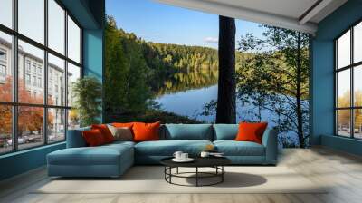 calm lake in bright sun light with reflections of clouds and trees and blue sky Wall mural