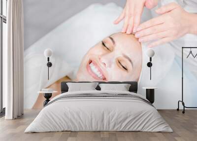 Beautician makes facial massage with mask. Beautiful smiling girl on spa procedure. Facial care. Wall mural