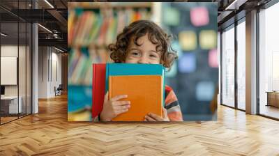 Happy boy cheerfully embraces colorful books lively learning environment. Curly-haired student happily poses books amidst school learning. Bond young student and his journey of learning. Wall mural