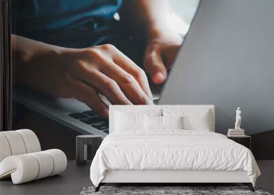 Male hands typing on a laptop resting on legs. Wall mural