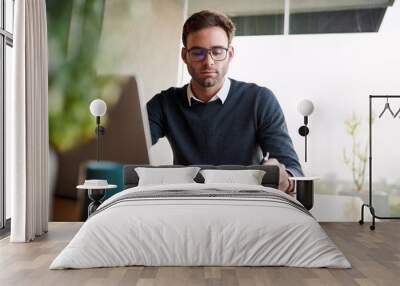 Businessman making notes while working on a laptop at home Wall mural