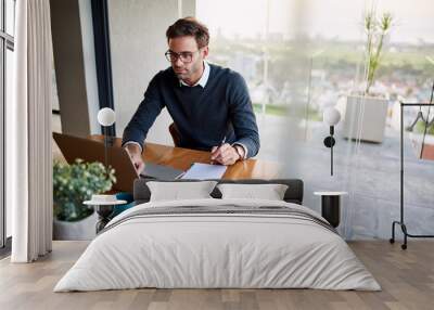 Businessman writing notes while working from home on a laptop Wall mural