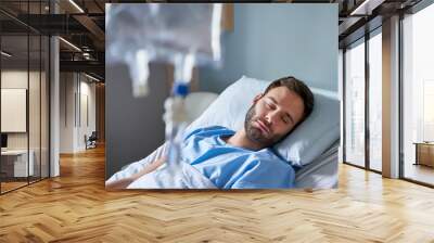 Sick young man receiving an intravenous treatment in a hospital Wall mural