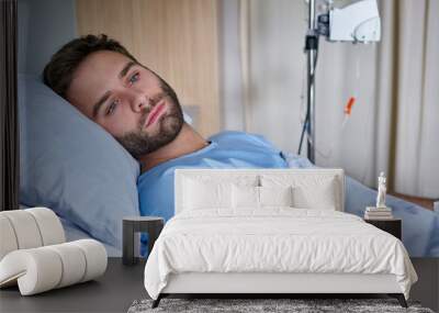 Sick young man recuperating on a bed in a hospital Wall mural