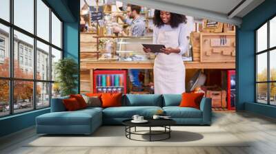 Smiling African American entrepreneur using a tablet in her cafe Wall mural