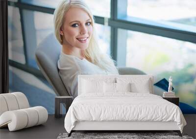 Smiling young businesswoman working by windows in a modern office Wall mural