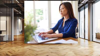 Young Asian businesswoman working from home on a laptop Wall mural