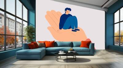 Sad man sits on the big human hand and needs care and support. Counselor helps a lonely teenager boy to get rid of depression. Support and care concept for people under stress. Vector illustration Wall mural