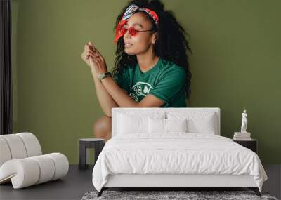 attractive black african american woman posing in stylish hipster outfit on green background Wall mural