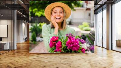 beautiful young woman in summer style outfit smiling happy walking with flowers in city street Wall mural