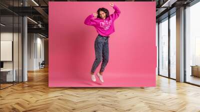 hispanic pretty woman in pink hoodie smiling jumping Wall mural