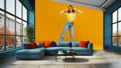 stylish happy smiling blond woman posing in jeans on yellow background Wall mural