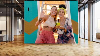 two stylish beautiful women relaxing having fun on beach in summer fashion trend outfit Wall mural