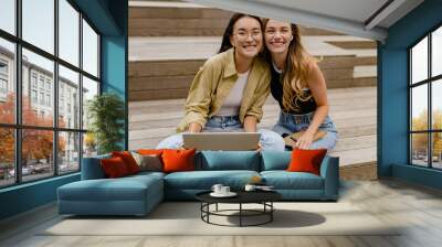 two young pretty women sitting in student campus co-working outside Wall mural