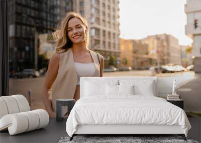 woman walking in sunny city street with phone Wall mural