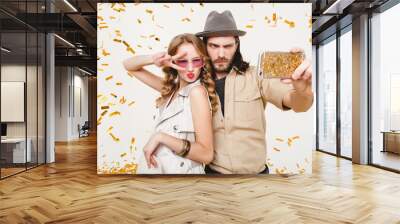 young stylish hipster couple in love making self photo, celebrating disco party, having fun, amazed, exited, funny face, golden confetti, holding phone, trendy apparel, cruise style, white background Wall mural