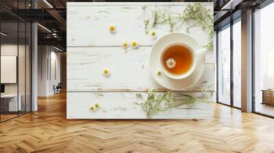 A cup of chamomile tea, shot from the top on a white wooden background with a bouquet of flowers and a place for text Wall mural