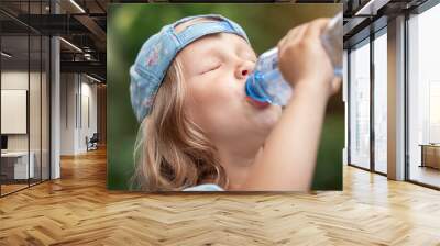 Drinking Water from Bottle. Thirsty Child Little Girl Baby Drink Water on Green Nature Background Outside. Wall mural