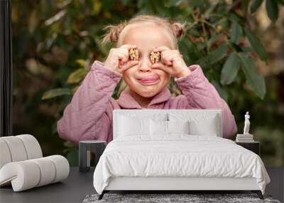 Walnuts in Child in front of Eyes on Nature Background. Peeled walnuts in Сhildren hands. Nuts for Children. Eco Food for Children concept.  Wall mural