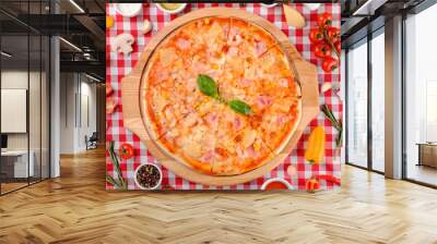 Hawaiian Italian pizza with parmesan cheese, pineapple, corn, ham toppings, fresh basil and tomatoes sauce on a wooden board, rustic village background, top view. European cuisine Wall mural