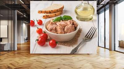 Canned tuna meat in a bowl, fork, bread and fresh red cherry tomatoes on a white wooden table. Low calories healthy eating snack of preserved tuna fish and vegetables. Tasty seafood. Wall mural