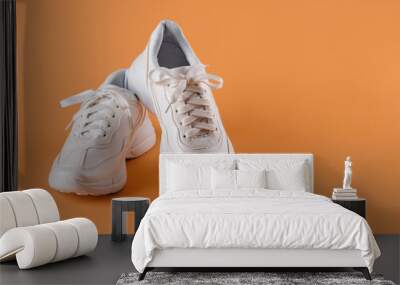 Pair of white tied laces sneakers over an orange background. New unisex chunky sole shoes for active lifestyle, fitness and sports. Copy space. Wall mural