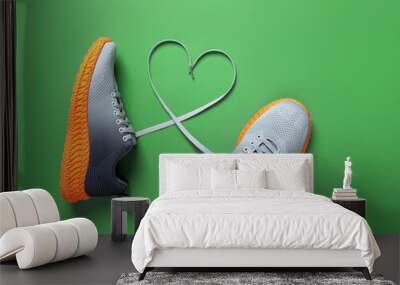 shoelace heart symbol between gray textile sneakers with grooved orange sole on grassy green backgro Wall mural