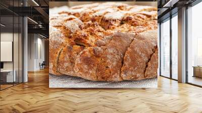 Sliced round loaf of rye bread with an appetizing crispy brown crust on a gray linen tablecloth. Tasty, usefull and nutritious. Front view, close-up, selective focus. Wall mural