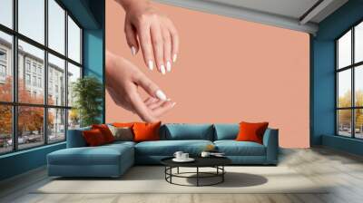 Hands of a beautiful well-groomed woman with feminine nails on a beige background. Manicure, pedicure beauty salon concept. Empty space for text or logo. On nails white gel polish Wall mural