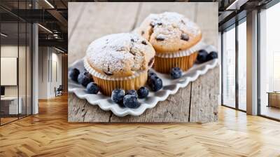 Homemade fresh muffins with sugar powder and blueberries on ceramic plate on rustic wooden table. Wall mural