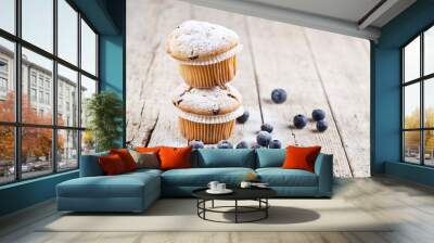 Two fresh homemade muffins with blueberries on rustic wooden table background.Two fresh homemade muffins with blueberries on rustic wooden table background. Wall mural