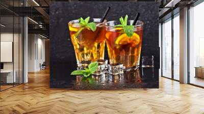 Two glasses with cold traditional iced tea with lemon, mint leaves and ice cubes. Wall mural