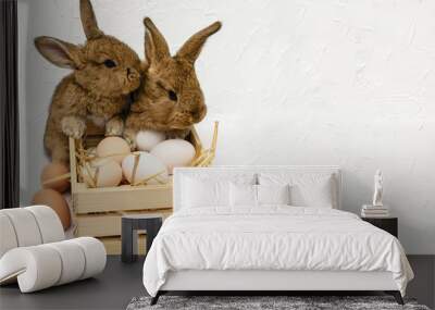 Cute little easter bunny with wooden box full of easter eggs Wall mural