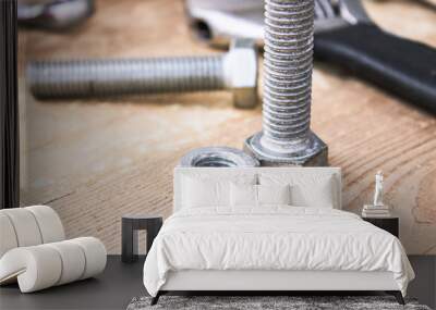 Steel bolts and nuts lie on wooden boards next to an adjustable wrench. Wall mural