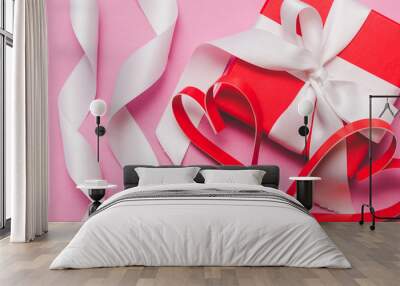 Red gift box tied with a white ribbon, two paper hearts on a pink background Wall mural