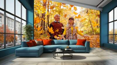 Fall season. Family couple throwing leaves in autumn forest. Senior people having fun outdoors enjoying nature Wall mural