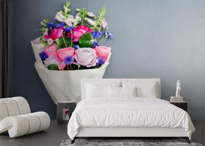 Fresh bouquet of roses foxgloves bachelor buttons flowers wrapped in paper and arranged on background. Wall mural