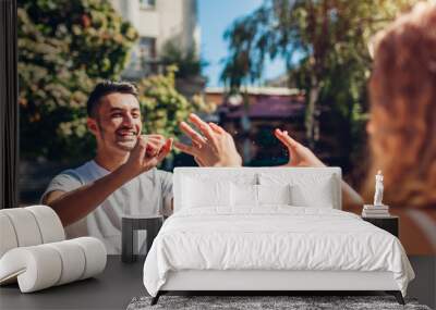 Happy multiracial couple playing by fountain in city. Man and woman sprinkle water on each other Wall mural