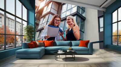 Real estate agent presenting new apartment to client. Businesswoman shows contract to customer. Partners laughing Wall mural