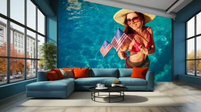 Sexy young woman holding USA flag in swimming pool. Celebrating Independence day of America Wall mural